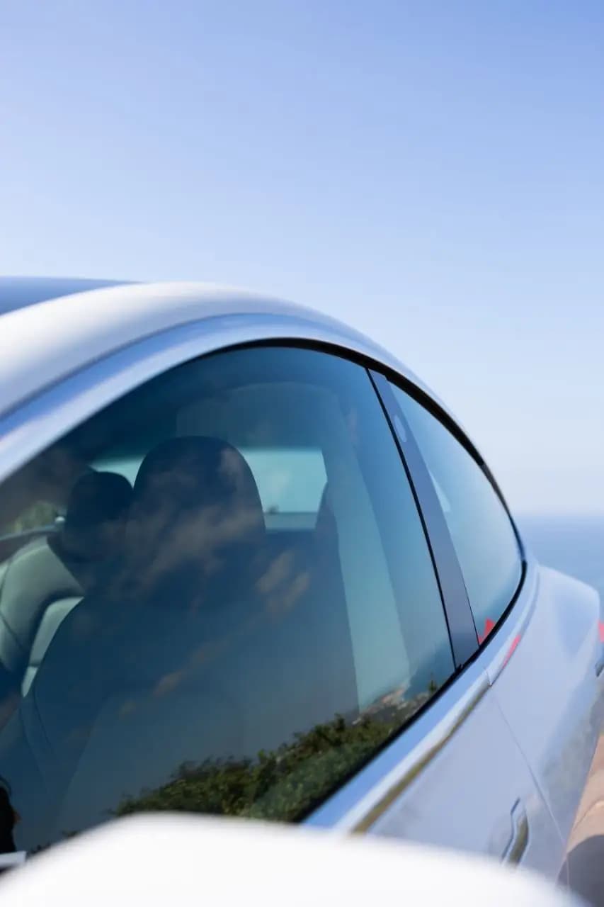 KAVACA IR tinted side window on a white car against a clear sky